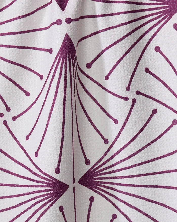 A close-up of the Libby Dark Maroon kitchen tea towel by Amy MacCready, featuring a white textured fabric with a repeating dark maroon geometric pattern of radiating lines and dots resembling abstract flower petals or fireworks.