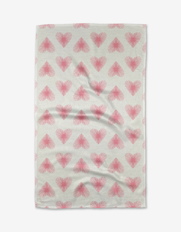 The Life Line Hearts tea towel by Hufton Studio features a beige background with rows of pink, radiating heart shapes. Made from Geoweave fabric, it has subtle wrinkles and is shown against a white background.