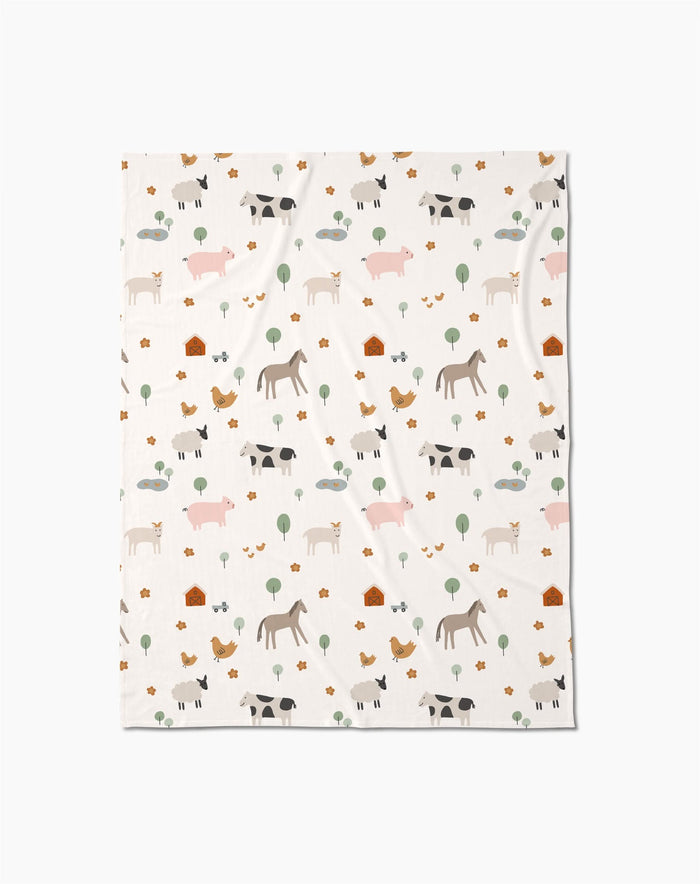 The Light Farm Animals Butter Blanket by Coit Creative is made from eco-friendly recycled materials and features soft pastel cows, pigs, horses, chickens, trees, and barns in a charming repeating pattern.