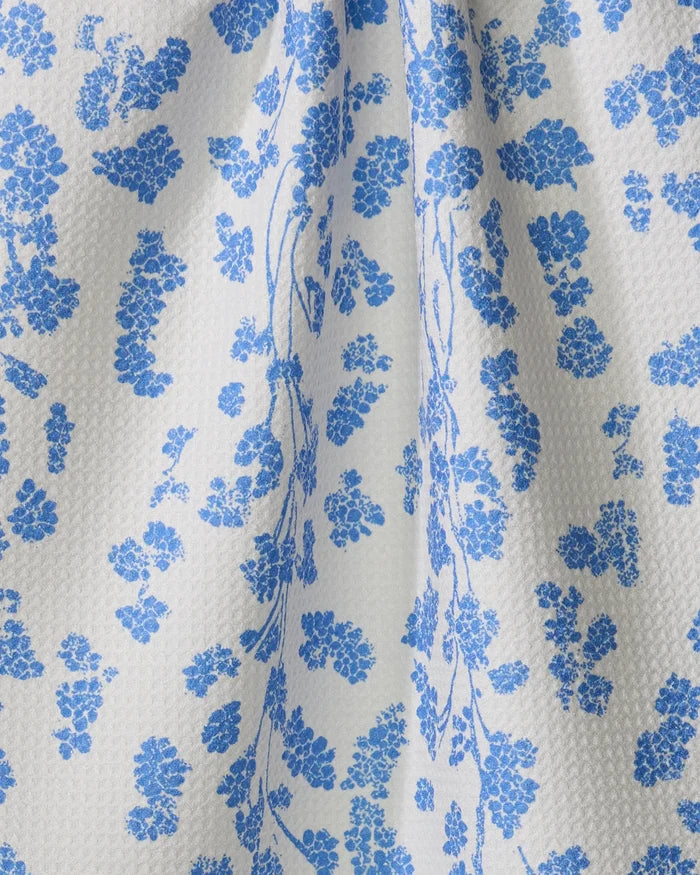 Close-up of Geometry's Lilou Cream dish towel featuring delicate blue floral clusters and vines on white, with soft draping that creates gentle folds and shadows.