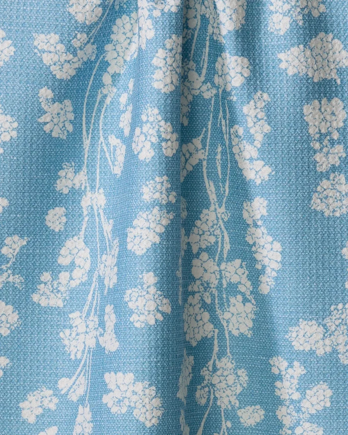 Geometry’s Lilou Light Blue kitchen towel features a light blue recycled fabric with a white floral pattern of clustered flowers and stems. The towel has a slightly textured look with soft folds and creases.