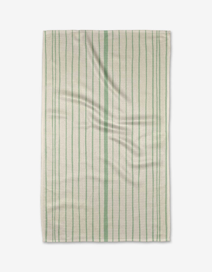 The Becki Owens Lily Stripe dish towel features a rectangular white design with ultra-absorbent, textured fabric and green vertical stripes, shown lying flat with gentle folds.