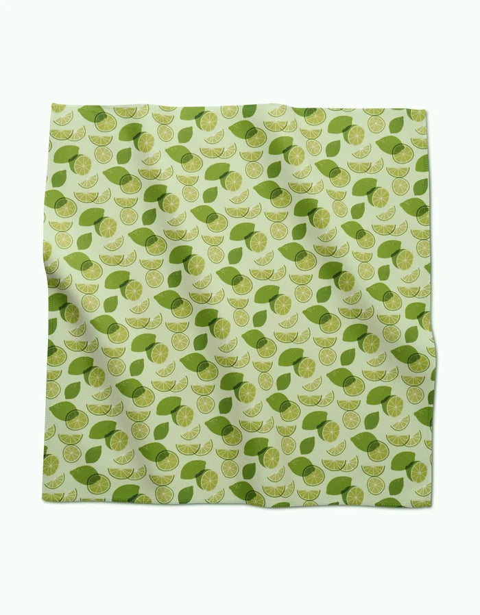 A square GEOMETRY Geosuede fabric piece, named Limes, features a repeating pattern of lime slices and green leaves on a light green background. Made from recycled materials, the fabric appears slightly wrinkled.