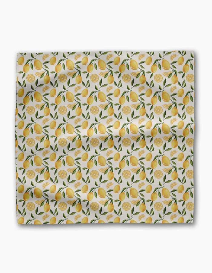 Geometry’s Limoncello Geosuede fabric features whole lemons, lemon slices, and green leaves on a white background—slightly wrinkled and displayed flat, ideal for creating a lively set of dinner napkins.