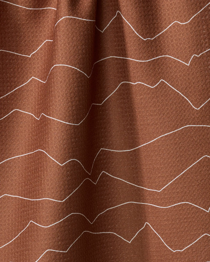 Close-up of Coit Creative's Lined Mountains tea towel, featuring brown textured fabric with white wavy lines resembling abstract mountains or topographic map patterns running horizontally.