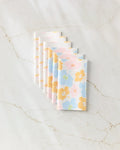 Seven Lobster Love napkins by GEOMETRY, featuring a red lobster print on eco-friendly paper towels, are neatly fanned out on a white marble surface with light brown veining.