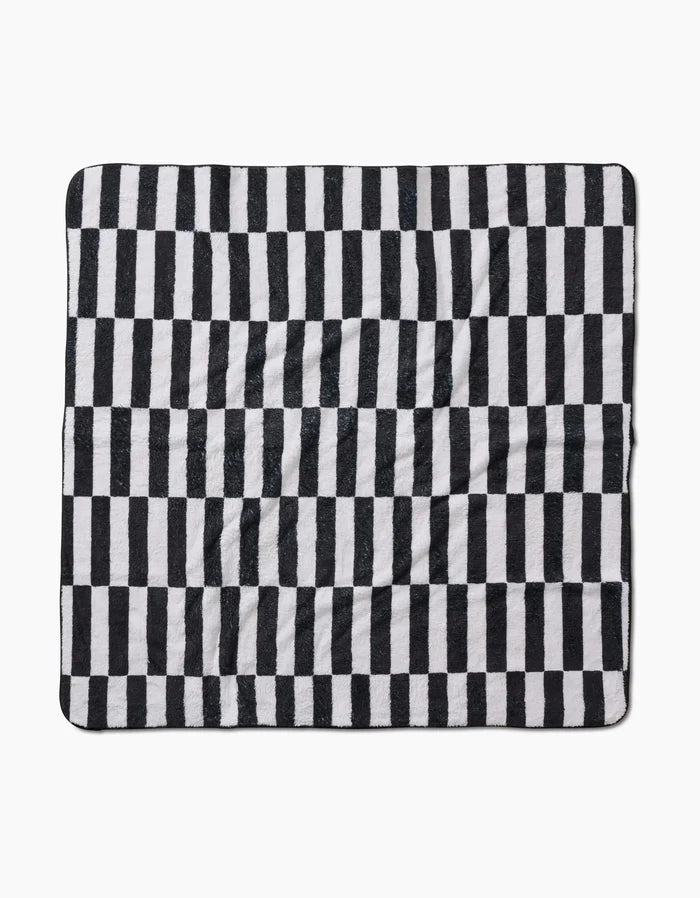 The Hufton Studio Long Check is a square blanket made from recycled materials, with a black and white vertical check pattern. Its ultra-absorbent fabric looks soft and slightly wrinkled, shown flat against a white background.