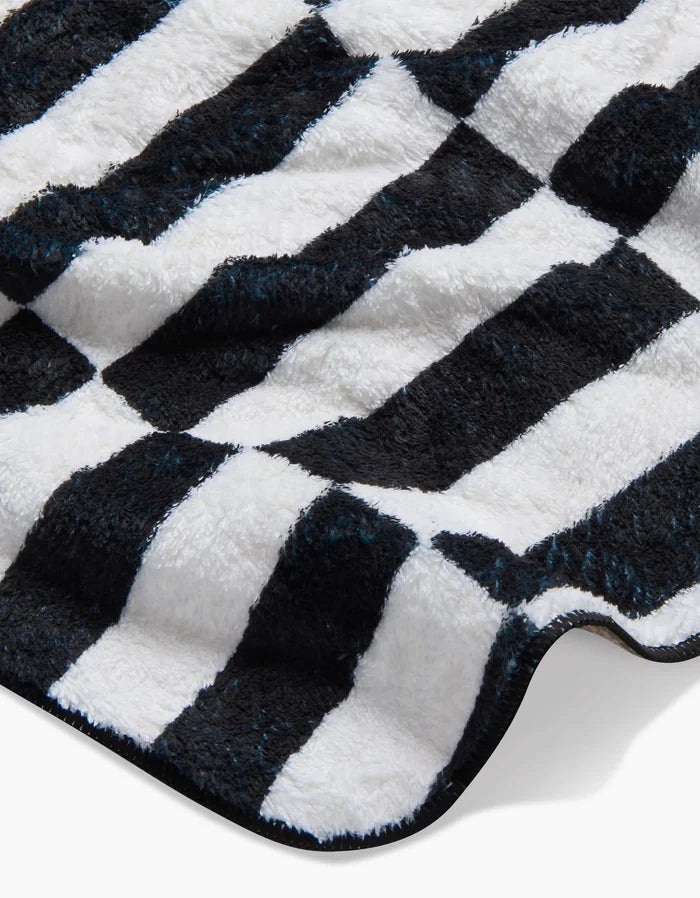 A close-up of Long Check, the ultra-absorbent plush dog towel by Hufton Studio, featuring soft recycled fabric with a black and white wavy check pattern for a cozy, eco-friendly touch.
