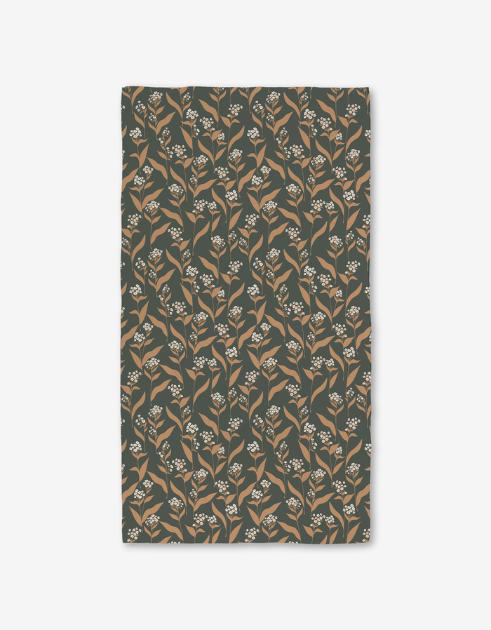 The Loretta bath towel by Charlie Rowan Designs features a rectangular shape and a beige and white floral pattern on dark green, crafted with Geoweave technology for ultra-absorbency.