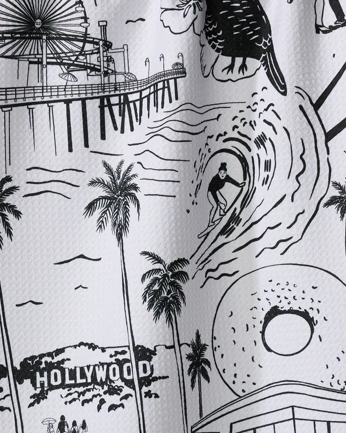 This absorbent dish towel by Elisabeth Wing, named "Los Angeles," features a black-and-white illustration of a surfer, palm trees, a pier ferris wheel, the Hollywood sign, and a donut—iconic scenes from California.