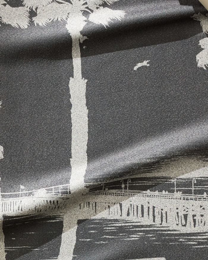 The Geometry Lost In Clemente fitness towel showcases a grayscale print of tall palm trees, a pier over water, and a flying bird, all on an ultra-absorbent, fast-drying fabric with subtle folds.