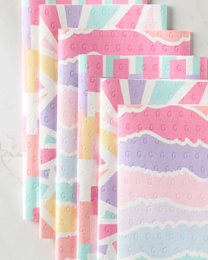 Five pastel-colored, patterned reusable paper towels from Rebecca Bobko’s Lots of Dots are overlapped, displaying wavy and striped designs in pink, blue, lavender, yellow, and white with a subtle "G" imprint throughout.