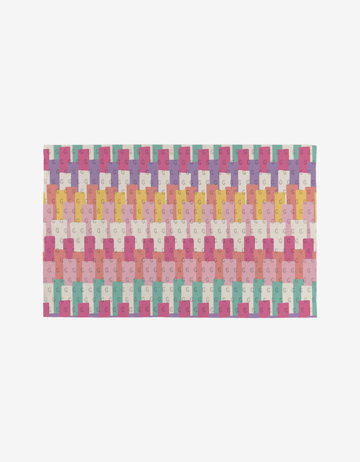 Lots of Dots by Rebecca Bobko is a reusable, rectangular mat with eco-friendly design, featuring interlocking pastel puzzle pieces in pink, yellow, green, blue, and white—each bearing a small G—set on a plain white background; not paper towels.