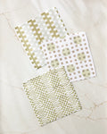 Three absorbent Lotty dishcloths by Studio Jeannot, in green and beige, lie on marble. The set features stylish geometric designs: checks, dots with circles, and zigzags.