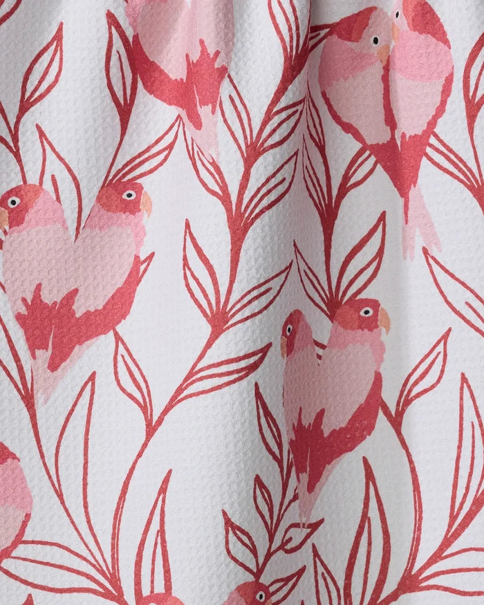 The Love Birds tea towel by Hufton Studio features pink and red birds with heart-shaped bodies perched on leafy branches, all set against a white textured background—a charming, recycled kitchen accessory.