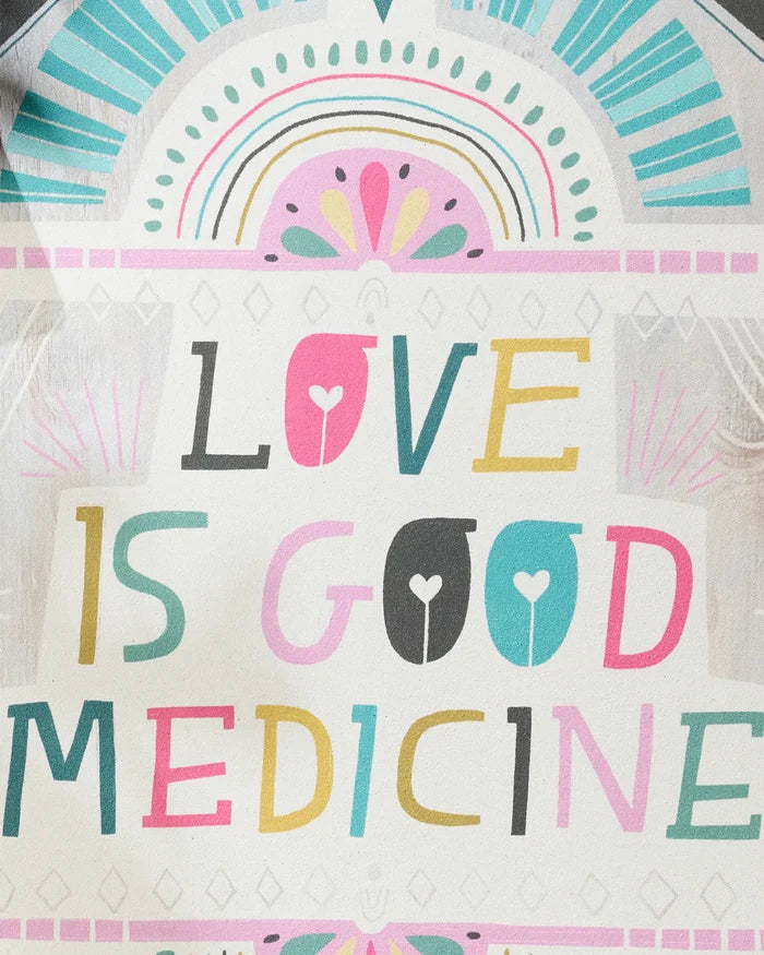 Brighten your yoga space with the "Love is Good Medicine" decorative sign by Jessica Swift, featuring playful multicolored letters and pastel designs—an ideal match for a non-slip yoga towel.