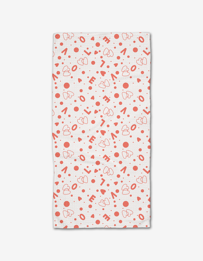 The “Love Party” bar towel from Charlie Rowan Designs is ultra-absorbent, white, and features a playful pattern of red hearts, dots, and scattered “LOVE” lettering.
