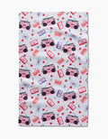 The Love Playlist tea towel by Vaishali Design Studio showcases pink and purple cassette tapes, boomboxes, red hearts, and black musical notes in a lively scattered pattern on white.