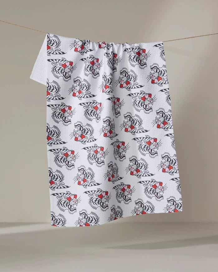 The Love Tiger by Cole Strem is a white textured cloth made from recycled materials, featuring a repeating black floral pattern with small red accents, hanging on a string against a plain light background.