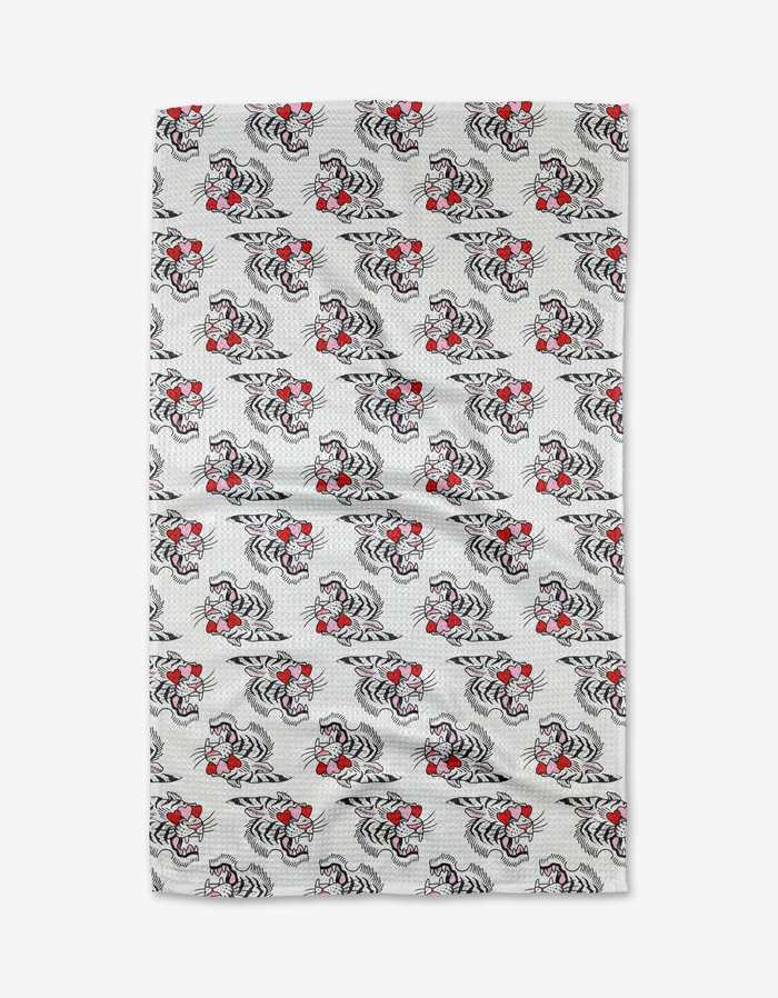 A rectangular tea towel by Cole Strem named Love Tiger, featuring repeating black and white tiger patterns with red bowties on a white dotted background, crafted from recycled materials.