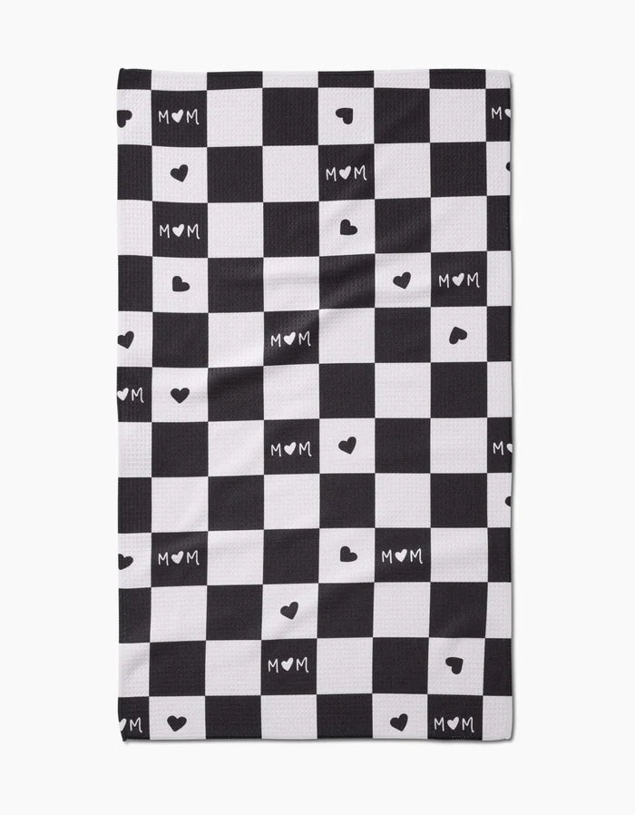 The GEOMETRY Loving Tea Towel features a black and white checkered pattern with MOM and small hearts in some white squares, crafted from soft Geoweave fabric.