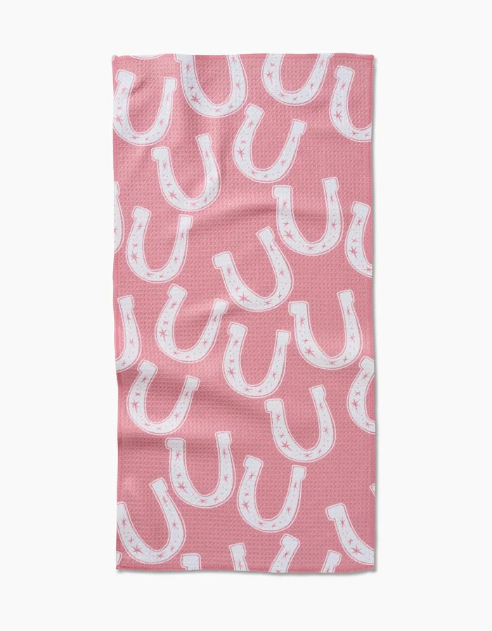 The Aubrey Fairchild “Lucky Horseshoe” bar towel features a pink Geoweave fabric with a repeating white horseshoe and subtle star pattern in various orientations.