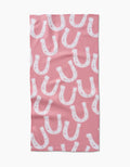 The Aubrey Fairchild “Lucky Horseshoe” bar towel features a pink Geoweave fabric with a repeating white horseshoe and subtle star pattern in various orientations.