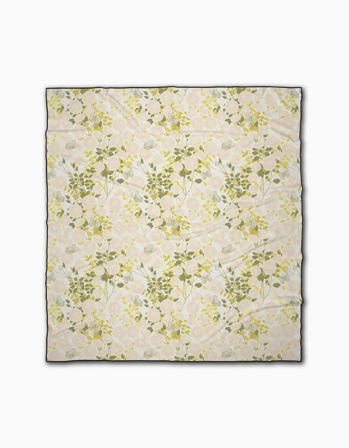 The Lush Garden rectangular beach blanket by Second Nature Studio features a soft, pastel floral print on cream and is made from quick-drying recycled materials. Shown flat on a white background.