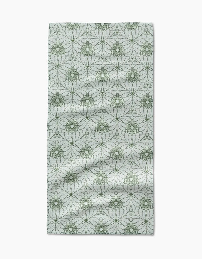 The Marta Harvey Lush Green Floral Bar Towel features ultra-absorbent Geoweave fabric with green, circular floral designs on a light gray background, showing natural folds and wrinkles.