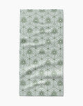 The Marta Harvey Lush Green Floral Bar Towel features ultra-absorbent Geoweave fabric with green, circular floral designs on a light gray background, showing natural folds and wrinkles.