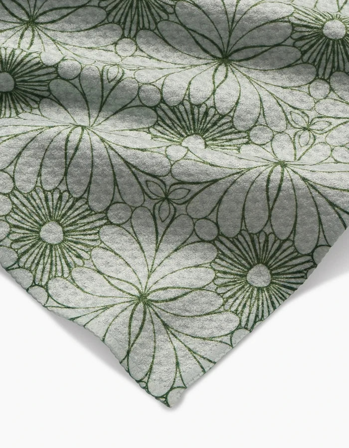 A close-up of Marta Harvey’s Lush Green Floral Bar Towel shows soft, ultra-absorbent light gray Geoweave fabric, featuring large, dark green outlined flowers and folded at the corner for a stylish touch.