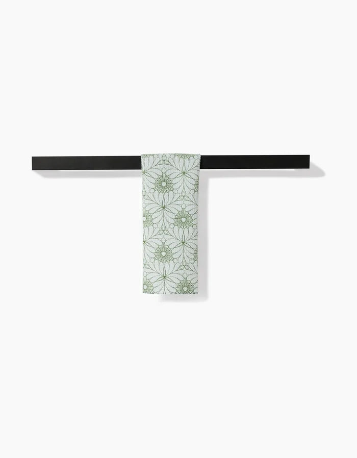 A Lush Green Floral bar towel by Marta Harvey hangs neatly on a horizontal black bar against a white background, showcasing its ultra-absorbent Geoweave fabric.