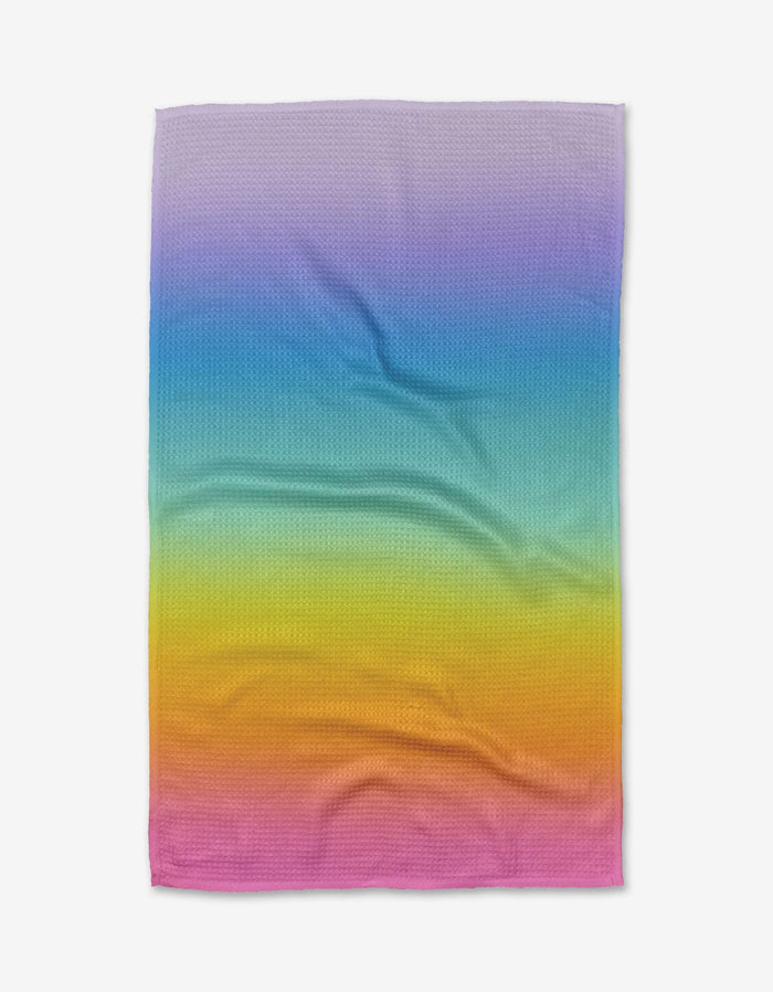 The Mac Joy towel by Noras Macarons is a rectangular, ultra-absorbent Geoweave™ fabric towel featuring a purple-to-pink gradient pattern, displayed slightly wrinkled on a white background.