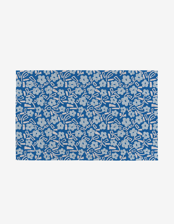 The Happy Hemera Magic Field is a rectangular blue mat featuring light gray flowers and abstract shapes on white—an eco-friendly choice made from post-consumer recycled materials.