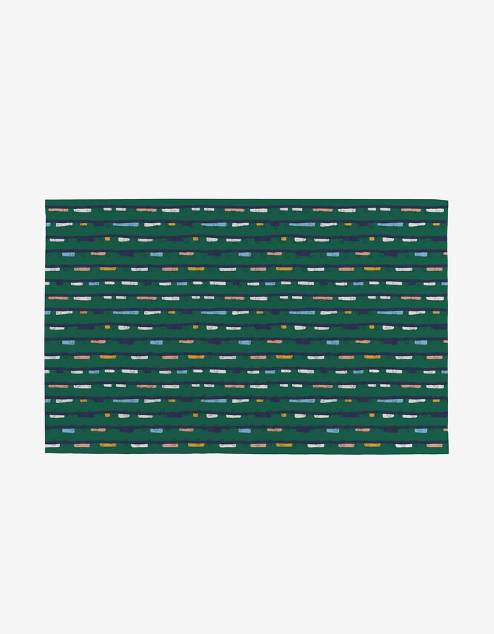 The Magic Field mat by Happy Hemera is a rectangular, flat green mat made from post-consumer recycled materials, featuring rows of evenly spaced blue, white, yellow, and gray dashes on a plain white background.