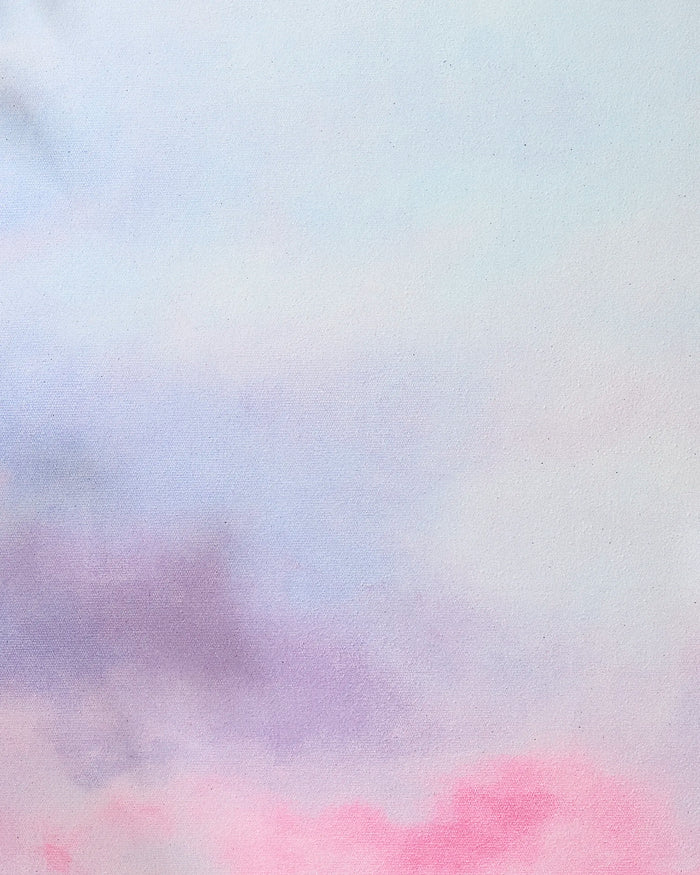 A soft pastel watercolor background with blended light blue, pink, and purple hues creates a dreamy scene—an ideal backdrop for displaying the "Magic in the Sky" recycled yoga towel by Stefanie Bales.