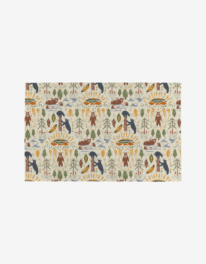 Mama Bear by Elisabeth Wing features a whimsical repeating pattern of bears, pine trees, mountains, rivers, and the sun on a light background. Printed on eco-friendly material, it adds playful woodland charm to any space.