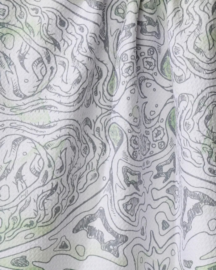 Close-up of the Manta tea towel by Skye Walker, crafted from recycled materials. Features a black and white abstract, symmetrical pattern with subtle green accents on softly folded, ultra-absorbent fabric.