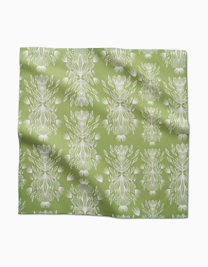Margarita Vibes by GEOMETRY features green Geosuede fabric with a repeating white floral and leaf print, subtle folds and creases, and is crafted from recycled materials for eco-friendly style.