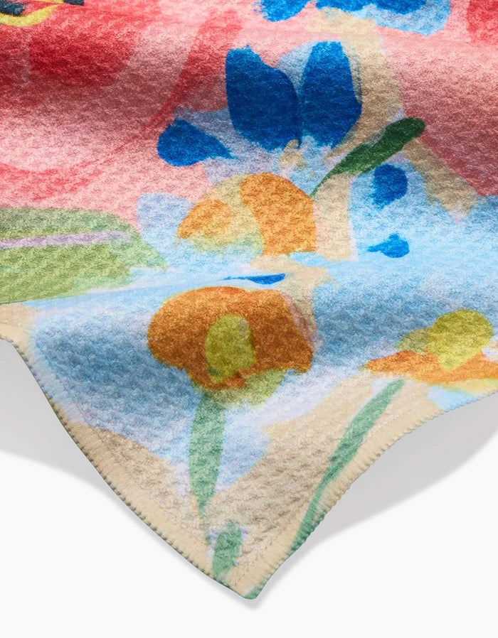 A close-up of the Margot Geoweave bar towel by Ania Zwara Art, showing its soft, textured fabric and vibrant abstract floral pattern in blue, orange, green, and red with a visible seam along the edge.