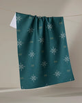 A Twig + Spark "Marine Navigation" tea towel, made from dark green Geoweave fabric with white starbursts and yellow accents, hangs on a line against a neutral background.