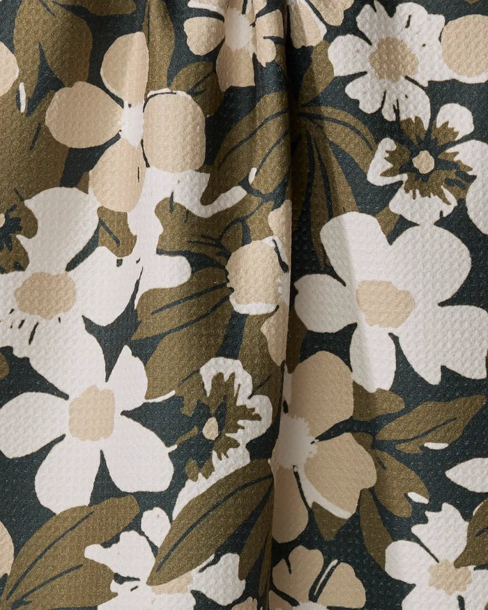 Close-up of the Marlo Brown tea towel by Geometry, featuring a textured floral pattern with large white and beige flowers and green leaves on a dark background, crafted from recycled materials.