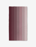 The GEOMETRY Mauve Levels Bath Towel features vertical stripes blending dark maroon to pale pink on white, and its Geoweave technology ensures ultra-absorbency and style for your bathroom.