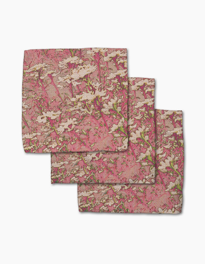 Three folded Geometry Maximist Floral handkerchiefs, made from super-absorbent Geoweave fabric with a white flower and green stem pattern, are stacked in a staggered arrangement on a white background.