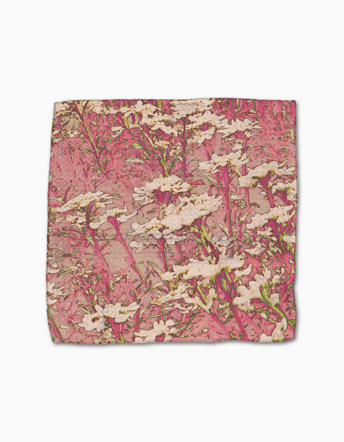 The Geometry Maximist Floral Geoweave dishcloth set features a vibrant pink background with white flowers and green stems, offering an artistic, super-absorbent rectangular cloth.