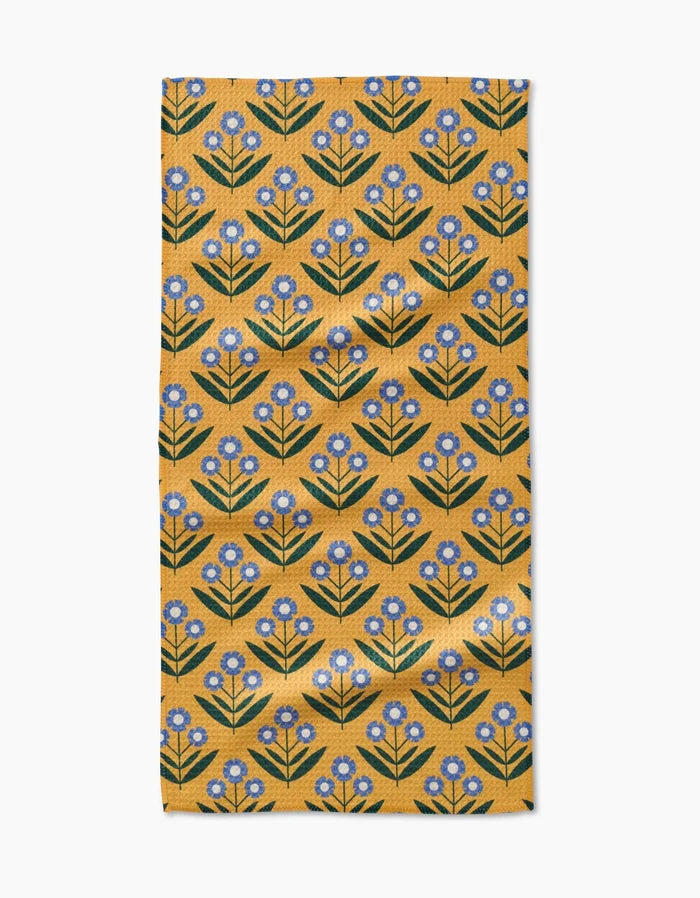 The Mayday Bar Towel by Megan Kampa features Geoweave fabric with a mustard yellow base and blue flowers with green stems arranged in neat diagonal rows.
