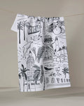 The Elisabeth Wing "Miami" kitchen towel is white, made from recycled materials, and features black line drawings of Miami landmarks, palm trees, a burger, cocktail, and the words HAVANA and BAYSIDE.