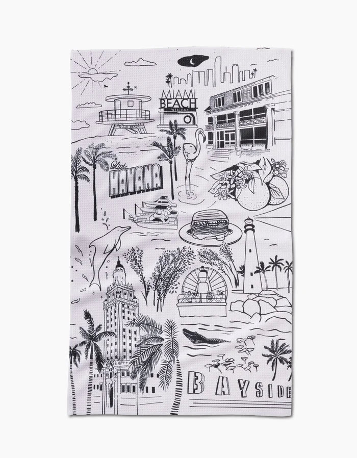 The Miami Tea Towel by Elisabeth Wing is made from Geoweave™ fabric and features black line drawings of Miami landmarks, including palm trees, Art Deco buildings, and dolphins, with “Miami Beach,” “Havana,” and “Bayside” boldly displayed.