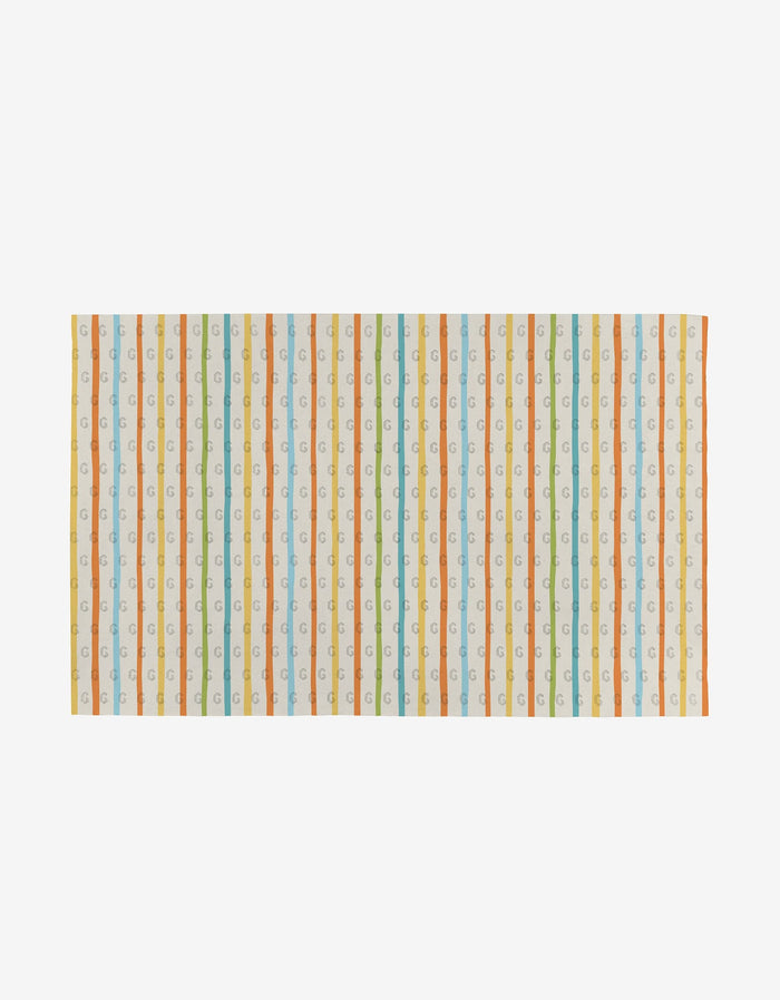 The Mindful Medley by Mindfulnice is a rectangular fabric towel with vertical stripes in orange, green, yellow, and light blue, plus a repeating small letter “G” on white. This reusable design offers an eco-friendly alternative to paper towels.