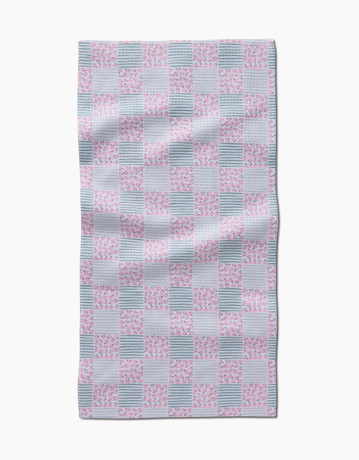 The Hufton Studio Mini Flowers and Stripes Check Pink and Green Bar Towel has a rectangular shape with alternating pink floral, green check, and striped squares, crafted from slightly wrinkled Geoweave fabric.